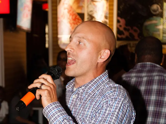 The person wearing a black belt is standing and singing in front of a mike and there are also a...