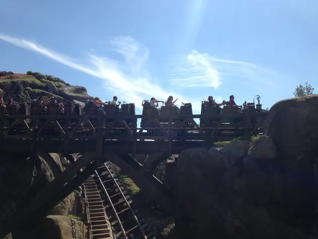 In this image there are a few people riding on a roller coaster, in the background of the image...